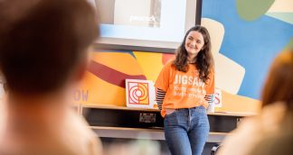 young woman in front of colourful background wearing jigsaw tshirt