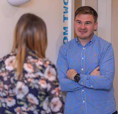 two people talking, one facing the camera and one has their back to it