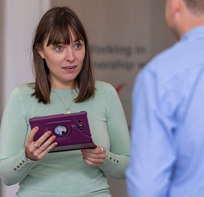 clinical manager using an ipad to do a questionnaire with someone who has their back to the camera
