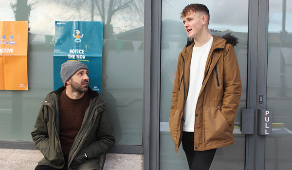 Young man talking to adult Young man talking to adult on side of street