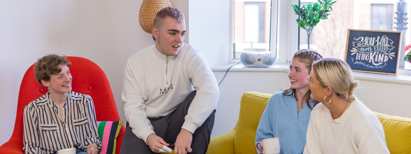 four young people sitting inside chatting