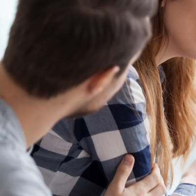 Close up of a a person comforting another, specifically a hand on their shoulder