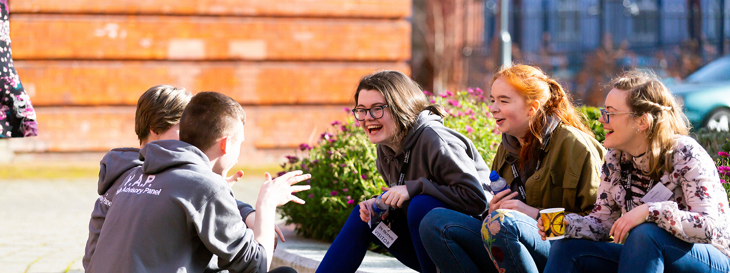 young people sitting on the ground chatting and laughin