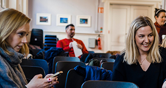 woman talking at workshop and one using her phone