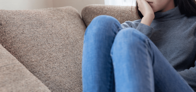 A girl sitting on a couch with her hand to her face