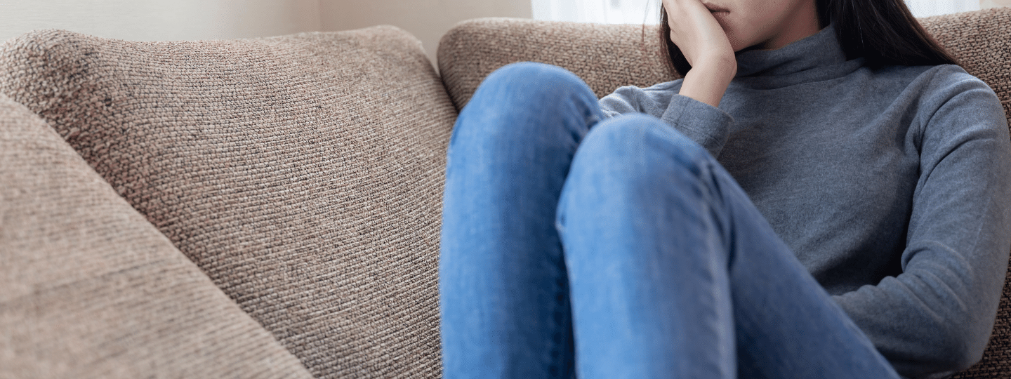 A girl sitting on a couch with her hand to her face