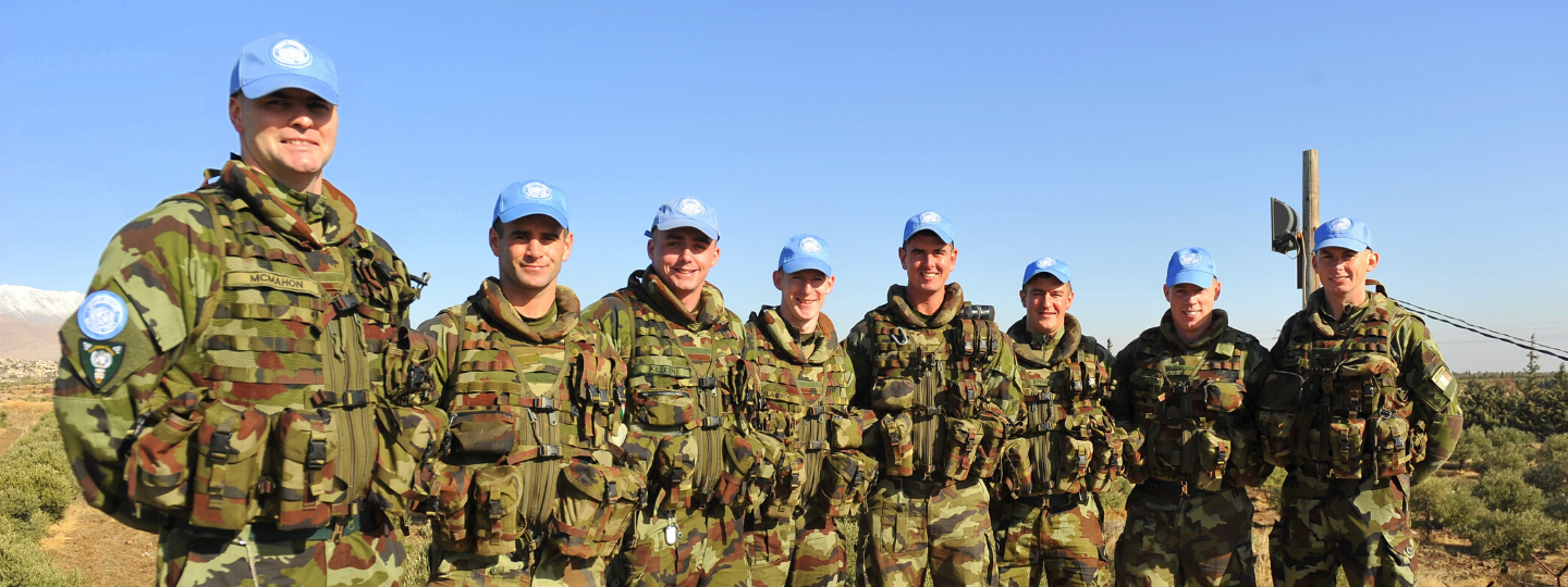 A close up of a computer keyboard, next to a notebook and cup of coffee